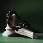 Blackened Black Mamba rope bracelet displayed on a green sculpture