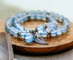 Blue chalcedony wrap bracelet with silver-tone spacers and a leaf charm on a wooden display