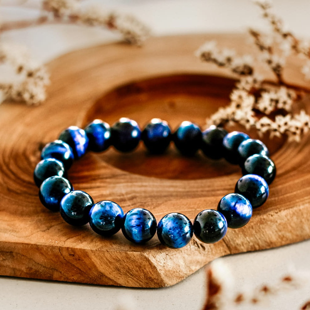 saltlume.com Blue Tiger's Eye Bracelet - polished blue and black tiger's eye beads on a wooden display