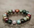 Indian agate bracelet with polished green, brown and pale stone beads on a textured surface