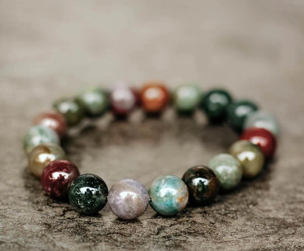 Indian agate bracelet with polished green, brown and pale stone beads on a textured surface