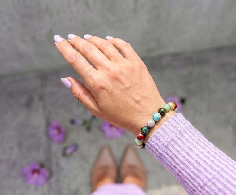 Mixed green and earthy agate beads worn on the wrist with a lilac knit sleeve