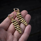 Pair of Rattlesnake Tail earrings held in hand