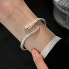 Snake-shaped open cuff bracelet worn on the wrist with a white cuff