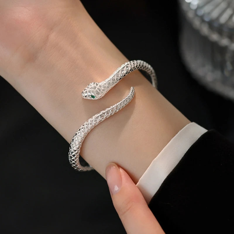 Snake-shaped open cuff bracelet worn on the wrist with a white cuff