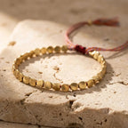Full bracelet showing the warm metal beads and braided sliding cord